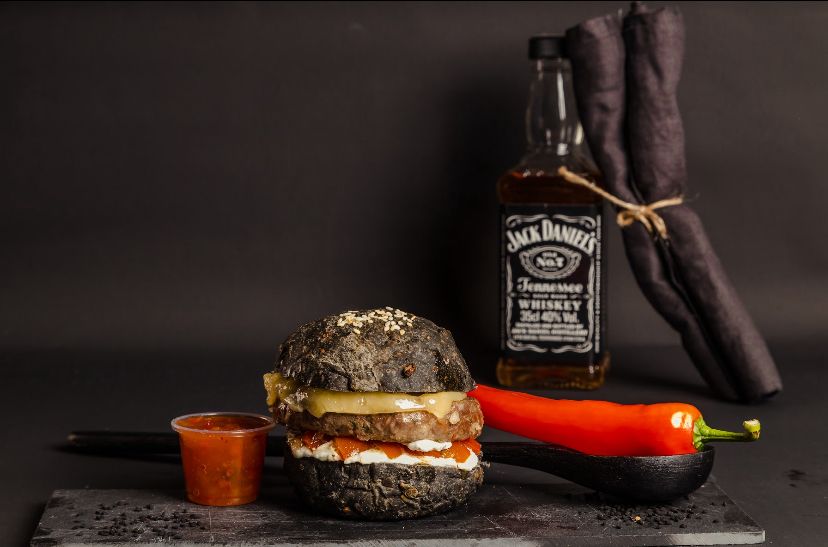 Beef burger served with homemade activated charcoal bread, tomato, cheese and special mayo.